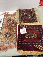 Full view of all three small Persian style carpets arranged with fringes visible showing size and color patterns.