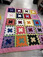 Full view of the entire quilt laid flat showing the overall bright patchwork design with 4x4 grid of colorful block patterns.