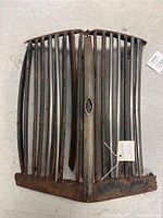 Full view of the antique metal grill with vertical bars and rust on the bottom edge and central strip.