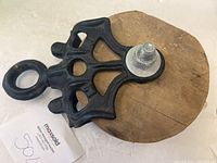 Pulley viewed from angled top showing wooden wheel and cast iron frame with eyehook attachment.