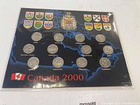 Full view of the Canada 2000 commemorative coin set with 12 coins displayed on a blue background featuring provincial crests and the Canada 2000 label.