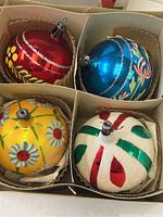 Top-down photo showing all four hand-painted Christmas ornaments snug in original box compartments.
