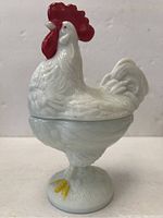 Front view of milk glass footed chicken container showing full profile and pedestal base.