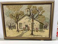 Photo of the full framed hook rug showing stone building with surrounding trees in earthy colors