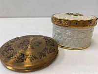 Side and top view of the Stratton brass compact and Lenox powder jar showing decorative details.