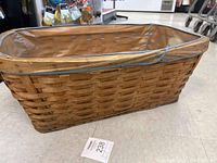Full view of rectangular lined wood slat laundry basket with two handles on the ends.