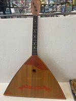 Front view of vintage 3-string guitar with triangular body and wood finish showing Mockba 80 branding.