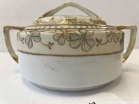 Front side view of Nippon biscuit barrel showing cream base with green clover leaf and gold paint decoration, some wear visible on gold paint.
