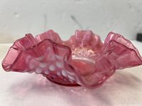 Small cranberry-colored glass bowl with ruffled and star-shaped edges, hobnail pattern along the sides, featuring an opalescent finish with white highlights.