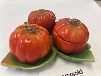 Close-up photo of the pumpkin-shaped salt and pepper shakers and pumpkin container on a green leaf-shaped tray.