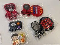Six silicone popper toys themed with Squid Game characters and symbols, all individually wrapped in plastic.