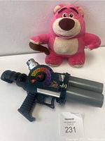 Photo showing the pink Lots-o'-Huggin Bear plush and the Emperor Zurg ball blaster toy gun together.