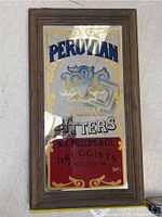 Full view of wooden framed vintage mirrored sign with Peruvian Tonic Bitters advertising and decorative gold and blue accents.