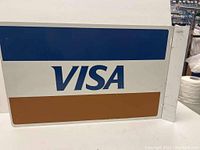 Close-up of one side of the sign showing the Visa logo and blue and gold bands.