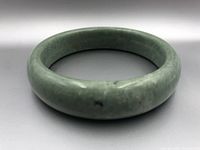 Front angle of the Chinese jade bangle showing rounded form and color variations in the stone.