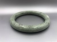 Side perspective of the light green jade bangle showing its rounded thick profile and polished shine.