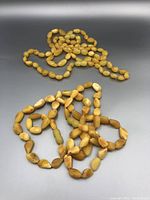Two egg yolk amber bead necklaces laid out, showing different bead sizes and shapes.