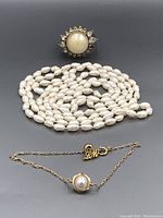 Photo showing three items: a pearl ring with halo setting, pearl necklace, and pearl bracelet.