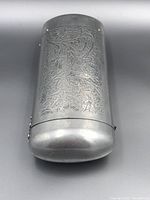 Front view of the silver cigar case showing detailed embossed floral and scrollwork chasing.