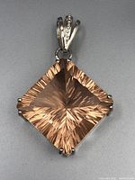 Front view of silver pendant showing large faceted light brown square gemstone with prong setting and decorated bail