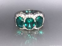 Front view of silver ring with three bright green oval gemstones and decorative silver detailing.