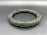 Front angle view of spinach jade bangle showing smooth round shape and natural green color variations.