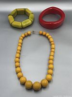 Full set of two bracelets and one necklace on grey background