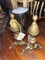 View of andirons and metal bucket together on wooden floor with packing peanuts in bucket