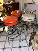 Three vintage bar stools grouped together, showing overall colors and design.