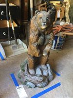 Full view of standing bear statue on base in garage setting