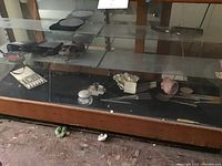Showcase of multiple items including binoculars, utensils, and vase inside display case.
