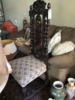 Chair angled view showing detailed upholstery and carved wood frame