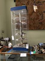 Overall view of tall display case with rotating shelves and blue top and bottom