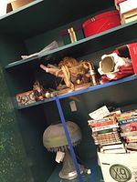 General view of shelving unit showing the cut lead crystal base lamp with hanging prisms, stacks of Christmas fabric covered boxes, tassels, and fabric covered hangers. Millennium angel tree topper visible on middle shelf.