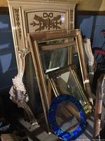 Multiple mirrors and one empty frame stacked together showing variety of shapes and frame styles.