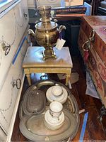 Photo of samovar on footstool with teacups, trays, and covered bowl on floor