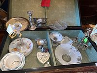 Photo showing various serving bowls, decorative bowls, crystal and glass candlestick, salt and pepper shakers in a display case.