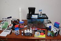 Full view of aquarium tank on dresser and assorted fish care and aquarium accessories around it.