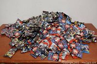Large pile of assorted sealed blind bag figure packs on a table.