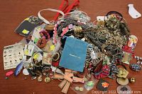 Top view of assorted costume jewelry spread on surface, showing various necklaces, bracelets, charms, and pins.
