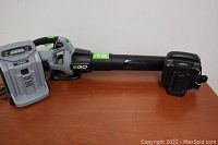 Full kit on wooden surface showing blower, battery installed, and charger alongside