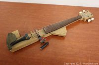 Full view of homemade electric violin showing wooden body, neck, fingerboard, strings, tailpiece with chin rest, and electronic components mounted near bridge.