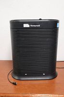 Front view of black Honeywell HPA300C air purifier showing grille and power cord.