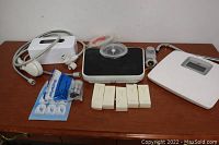 Lot contents showing bathroom scales, shower head, shave kits, wall hooks, and metal object.