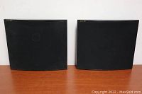 Pair of Jamo Art wall speakers shown side by side on wooden surface, front view with black fabric covers.