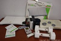 Wii accessories including two Wii Balance Boards, Wii Fit Plus game, original Gameboy handheld, Super Nintendo controller, and Wii Nunchuk controllers.