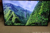 Television powered on displaying a vibrant scenic image of green mountains and waterfall