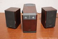 Sony SA-WEX200 speaker system with amplifier unit and two speakers shown on wooden surface.