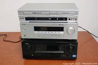 Stacked view of Emerson VHS/VCR combo, Yamaha HTR-5920 receiver, and Denon AVR-791 receiver on a wooden surface.