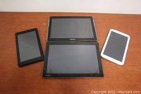 Four tablets on wooden surface, showing size and brand differences